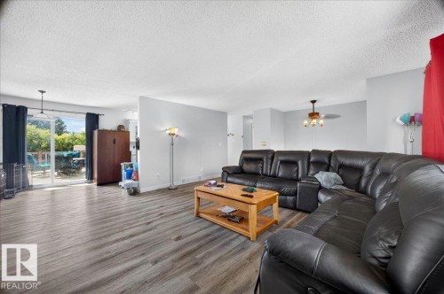 Spacious living area featuring wood-finish flooring, a neutral wall color, and a sliding glass door providing outdoor access - 5215 50 Avenue, Bruderheim, AB - Indoor Photo Showing Living Room