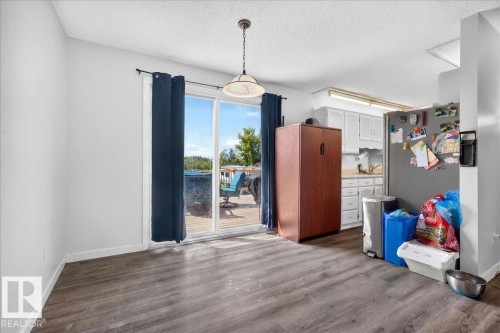 Kitchen area with wood-finish flooring and white cabinetry - 5215 50 Avenue, Bruderheim, AB - Indoor