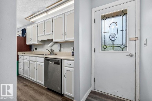 Kitchen area featuring white cabinetry, a stainless steel dishwasher, and a light-toned countertop - 5215 50 Avenue, Bruderheim, AB - Indoor Photo Showing Kitchen