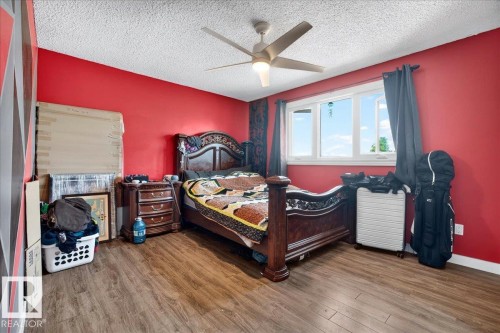 Interior room featuring wood-finish flooring, a white ceiling with a contemporary ceiling fan, and vibrant red walls - 5215 50 Avenue, Bruderheim, AB - Indoor Photo Showing Bedroom