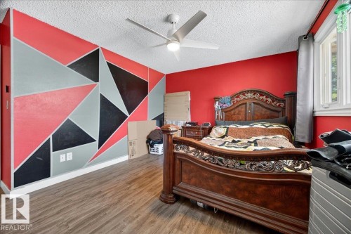 Spacious room featuring wood-finish flooring, a contemporary ceiling fan, and vibrant accent walls - 5215 50 Avenue, Bruderheim, AB - Indoor Photo Showing Bedroom