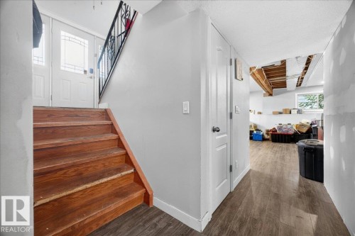 Wood-finish staircase leading to a landing with two white panel doors featuring decorative glass inserts - 5215 50 Avenue, Bruderheim, AB - Indoor Photo Showing Other Room