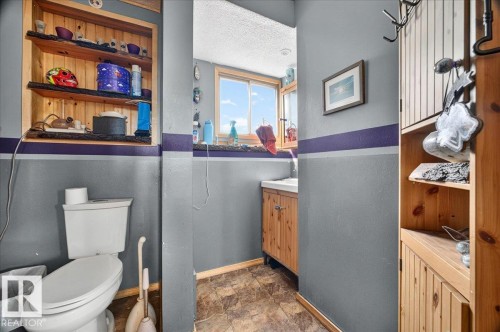 Full bathroom featuring a window, built-in wooden shelving, a vanity with a basin sink, and wood-finish flooring - 5215 50 Avenue, Bruderheim, AB - Indoor Photo Showing Bathroom