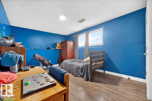 Room featuring wood-finish flooring, two windows with curtain rods, a ceiling light fixture, and a built-in air vent - 5215 50 Avenue, Bruderheim, AB - Indoor Photo Showing Bedroom