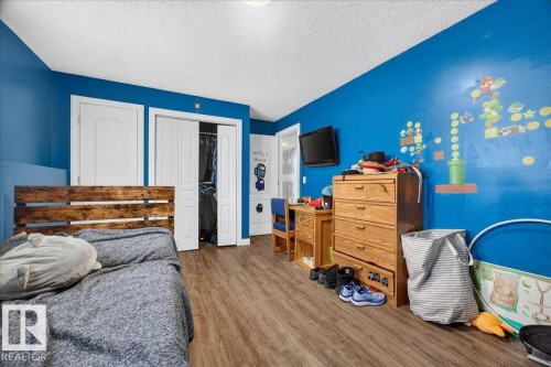 Wood-finish flooring with a vibrant blue wall accent - 5215 50 Avenue, Bruderheim, AB - Indoor Photo Showing Bedroom