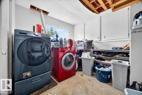 Laundry area featuring built-in upper cabinetry, white wainscoting, and a window providing natural light - 5215 50 Avenue, Bruderheim, AB - Indoor Photo Showing Laundry Room