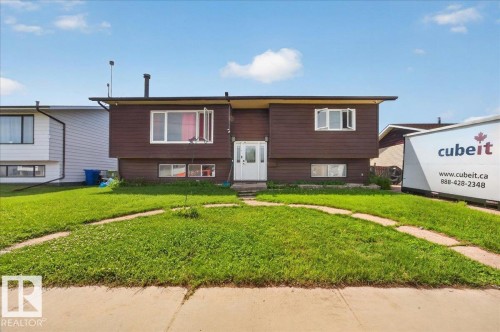 Brown exterior siding with white trim, featuring a central white entry door, multiple windows, and a front lawn with a paved pathway - 5215 50 Avenue, Bruderheim, AB - Outdoor