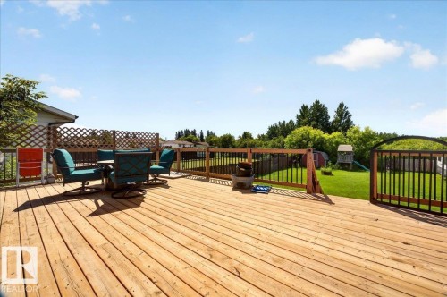 Expansive wood-finish deck with privacy lattice and railing, overlooking a generous green space - 5215 50 Avenue, Bruderheim, AB - Outdoor With Deck Patio Veranda With Exterior