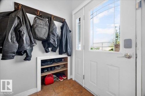 Entryway featuring a white paneled door with decorative glass inserts, a smart lock, and an integrated wood-finish coat rack - 5215 50 Avenue, Bruderheim, AB - Indoor