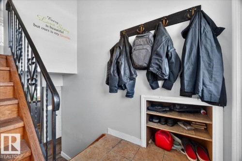 Hardwood staircase with decorative wrought iron railing, complemented by a built-in shoe storage nook and a wall-mounted coat rack - 5215 50 Avenue, Bruderheim, AB - Indoor