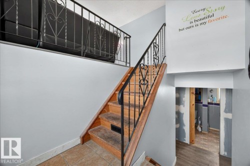 Wood-finish staircase with decorative wrought iron railing - 5215 50 Avenue, Bruderheim, AB - Indoor Photo Showing Other Room