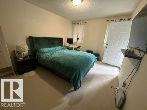 Carpeted interior space featuring a paneled door with hardware, a window with blinds, and a built-in shelf - 18020 96 Avenue, Edmonton, AB 