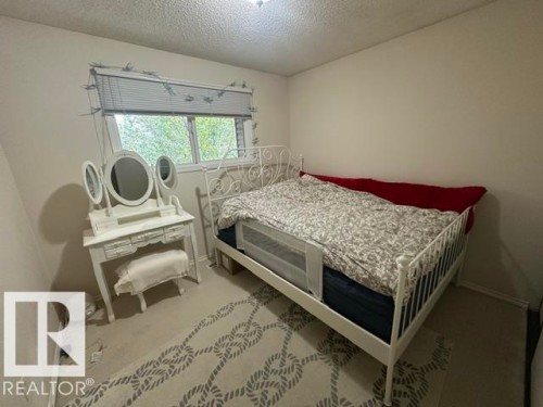 Carpeted room featuring a window with blinds, light-colored walls, and a ceiling light fixture - 18020 96 Avenue, Edmonton, AB 