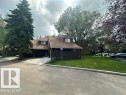 Townhome exterior featuring a brown facade, dormer windows, and a shingle roof - 18020 96 Avenue, Edmonton, AB 