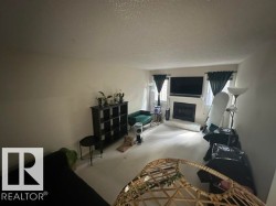 Living area featuring a white fireplace with a white mantel, two windows with dark curtains, and light-colored carpeting - 