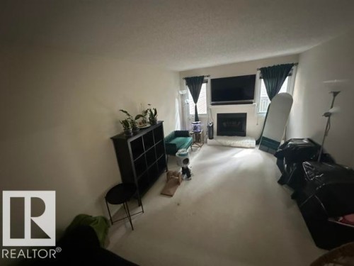 Living area featuring a white fireplace with a dark insert, flanked by two windows - 18020 96 Avenue, Edmonton, AB 