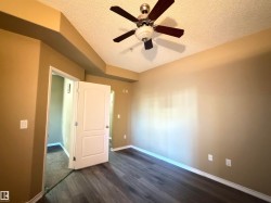 Spacious room featuring wood-finish flooring, a ceiling fan with integrated lighting, and neutral wall tones - 
