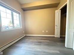 Room featuring wood-finish flooring, a large window with white framing, and a bi-fold closet door - 