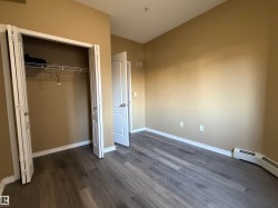 Room with wood-finish flooring, neutral wall paint, white baseboards, and a bi-fold closet with wire shelving - 