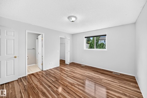 Spacious room featuring wood-finish flooring, light grey wall paint, and a window with white trim - 13124 36 Street, Edmonton, AB 