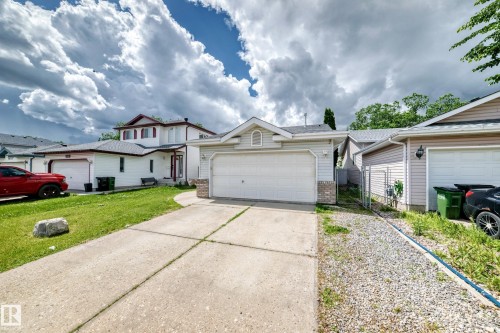 Front exterior featuring light-colored siding, an attached two-car garage with an overhead door, and a concrete driveway - 13124 36 Street, Edmonton, AB 