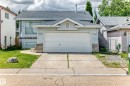 Light blue siding exterior featuring a prominent two-car garage with white door - 13124 36 Street, Edmonton, AB 
