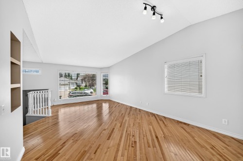 Open concept living area featuring wood-finish flooring, vaulted ceilings, and track lighting - 13124 36 Street, Edmonton, AB 