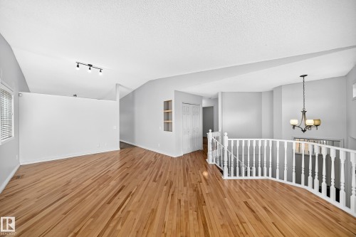 Open concept interior featuring wood-finish flooring, vaulted ceilings, and a white baluster railing - 13124 36 Street, Edmonton, AB 