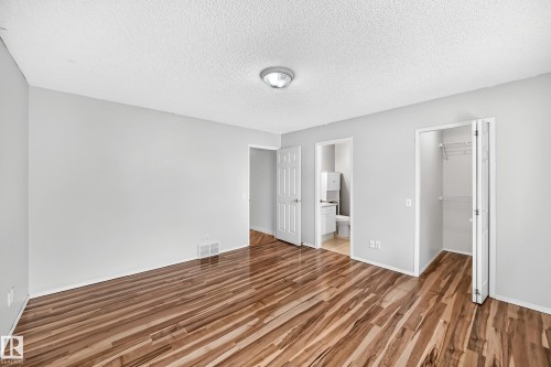 Spacious interior room featuring rich wood-finish flooring, light gray wall paint, and white trim - 13124 36 Street, Edmonton, AB 
