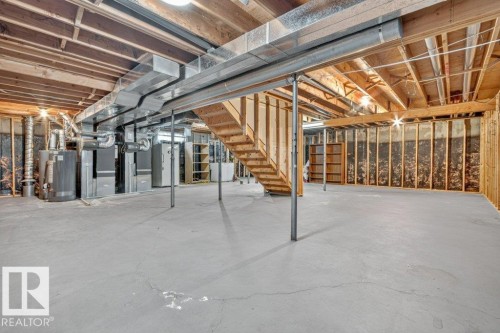 Spacious unfinished basement offering extensive potential for customization, featuring exposed ceiling joists, substantial open floor space, and visible HVAC ductwork - 16524 99 Street, Edmonton, AB 