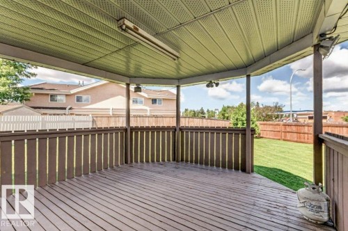 Covered outdoor deck with wood-finish flooring, surrounding dark wood-finish railing, and a slatted light-toned ceiling - 16524 99 Street, Edmonton, AB 