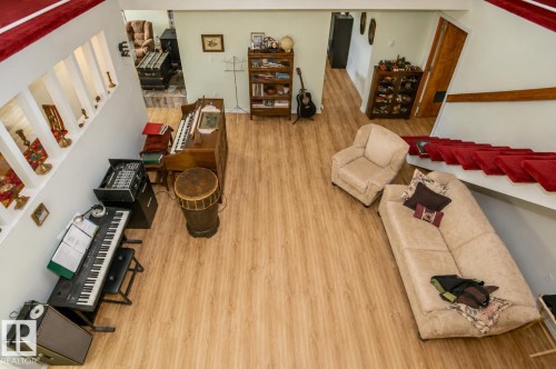 Open concept living area featuring wood-finish flooring, a white wall with integrated display niches, and a red carpeted staircase - 60528 Range Road 112, Rural St. Paul County, AB 