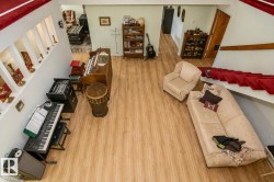 Open concept living area featuring wood-finish flooring, a white wall with integrated display niches, and a red carpeted staircase - 