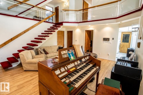 Open-concept living space featuring a floating staircase with red carpet treads and a wooden handrail - 60528 Range Road 112, Rural St. Paul County, AB 
