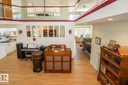 Open-concept interior featuring wood-finish flooring, a two-story ceiling, and a built-in kitchen - 