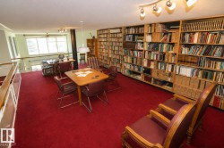 Loft space featuring extensive built-in wooden bookshelves, wall-to-wall red carpeting, and a track lighting fixture - 