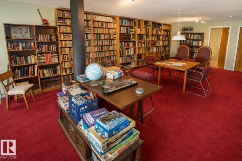 Expansive room featuring floor-to-ceiling built-in bookshelves, plush red carpeting, recessed lighting, and a white pendant light fixture - 60528 Range Road 112, Rural St. Paul County, AB 
