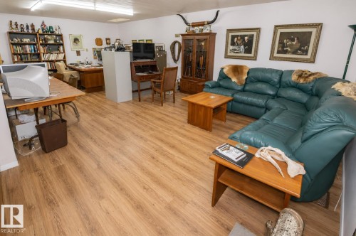 Spacious interior room featuring wood-finish flooring, white walls, and overhead fluorescent lighting - 60528 Range Road 112, Rural St. Paul County, AB 