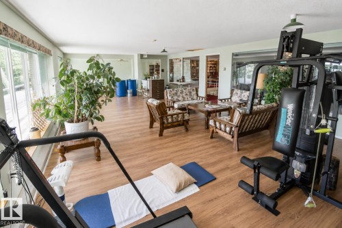 Expansive room with wood-finish flooring and abundant natural light from large windows - 60528 Range Road 112, Rural St. Paul County, AB 
