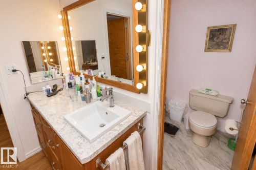 Vanity area featuring a vessel sink with a chrome faucet, light-toned countertop, and wood-finish cabinetry - 60528 Range Road 112, Rural St. Paul County, AB 