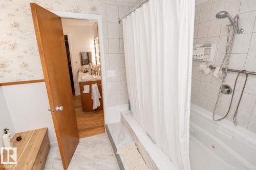 Bathroom featuring a tiled shower/tub combination with a wall-mounted showerhead, and grab bar - 60528 Range Road 112, Rural St. Paul County, AB 