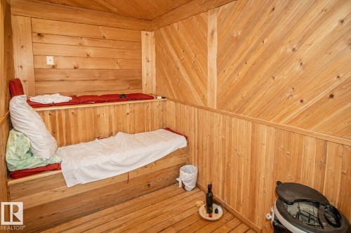 Wood-paneled room featuring a built-in multi-level bench, wood-finish flooring, and sloped wood-paneled walls - 60528 Range Road 112, Rural St. Paul County, AB 