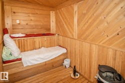 Wood-paneled room featuring a built-in multi-level bench, wood-finish flooring, and sloped wood-paneled walls - 
