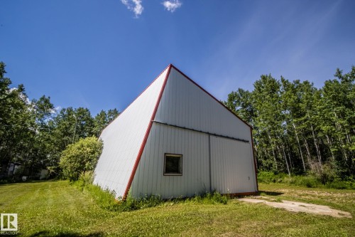 Metal-sided utility building with a steeply pitched red-trimmed roof - 60528 Range Road 112, Rural St. Paul County, AB 