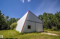 Metal-sided utility building with a steeply pitched red-trimmed roof - 