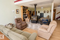 Living area featuring a freestanding wood stove on a tiled hearth, wood-finish flooring, and a built-in bookcase - 