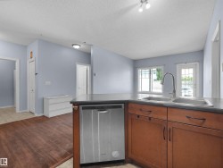 Kitchen island featuring a dual-basin stainless steel sink with a high-arch faucet, a built-in stainless steel dishwasher, and wood-finish cabinetry - 