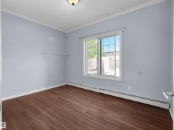 Interior room with wood-finish flooring, light blue wall paint, and white crown molding - 