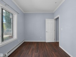 Room featuring wood-finish flooring, a multi-pane window with white trim, and a white panel door - 