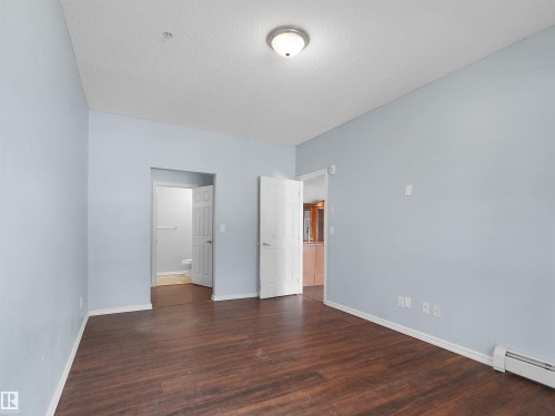 Spacious interior featuring wood-finish flooring, light blue wall paint, and white trim - 106 263 Macewan Road, Edmonton, AB 